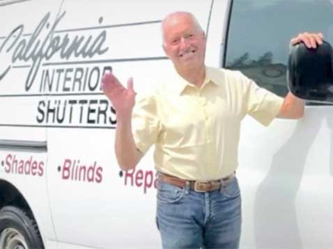A man smiling and waving, next to the company van